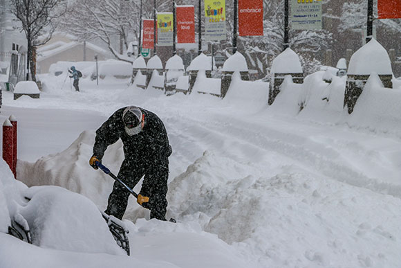 man shoveling lots of snow during epic winter on brooks alley