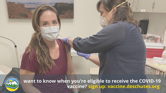 Image of woman receiving vaccine with text from Deschutes County that reads want to know when you're eligible to receive the COVID-19 vaccine? Sign up at vaccine.deschutes.org