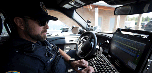 A City of Bend Police officer in his car working on his computer.