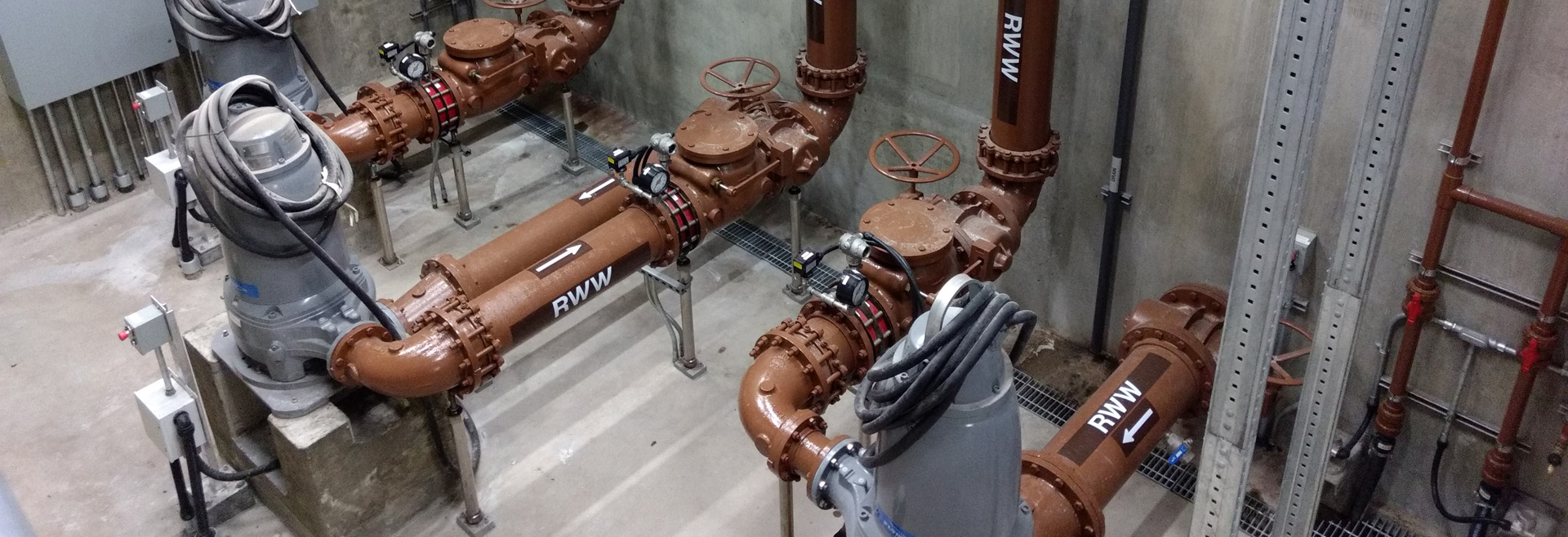 Pipes black in color attached to pumps that are maroon in color.