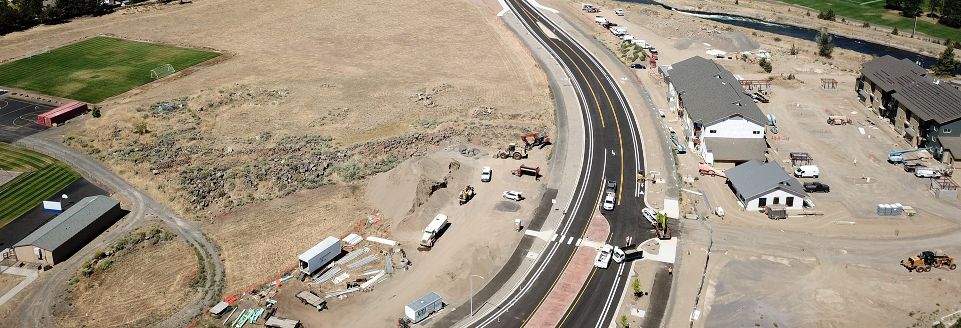 Drone shot overhead of empty land as well as land with construction of buildings and streets. Heavy equipment is shown.
