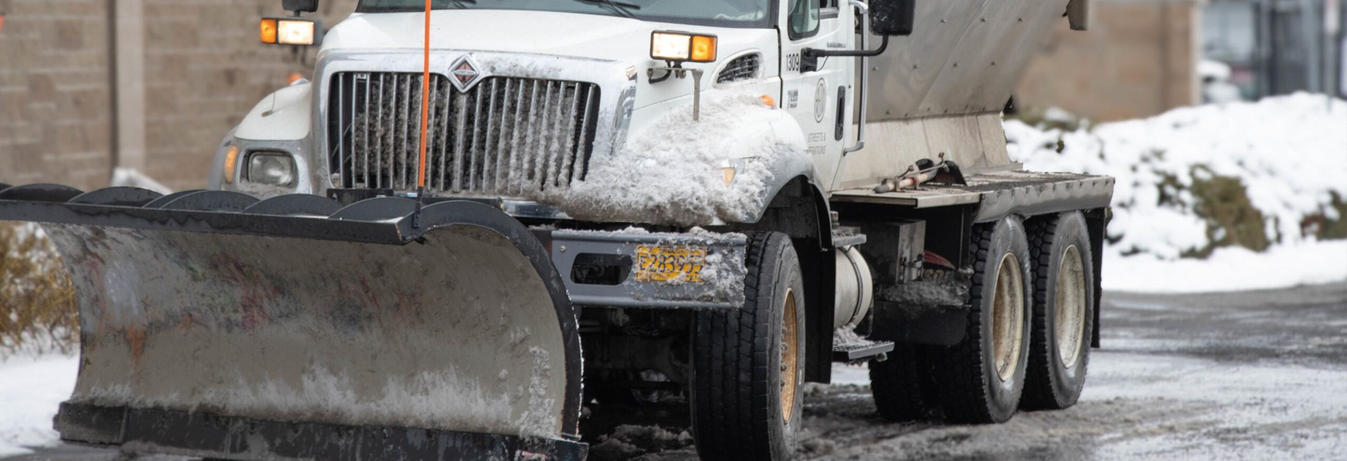 Snowplow that is plowing a city street during winter.