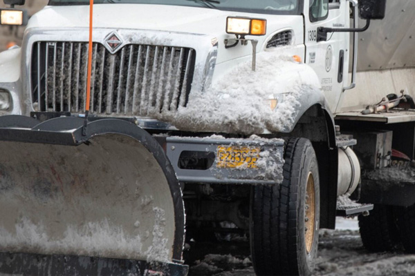 Snowplow plowing a city street.