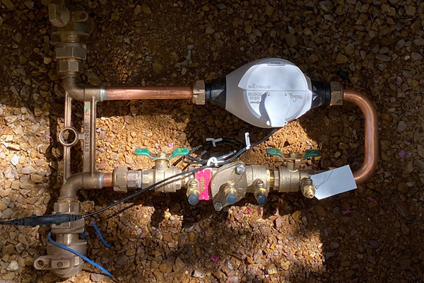 Water Meter inside of a box surrounded by brown earth.