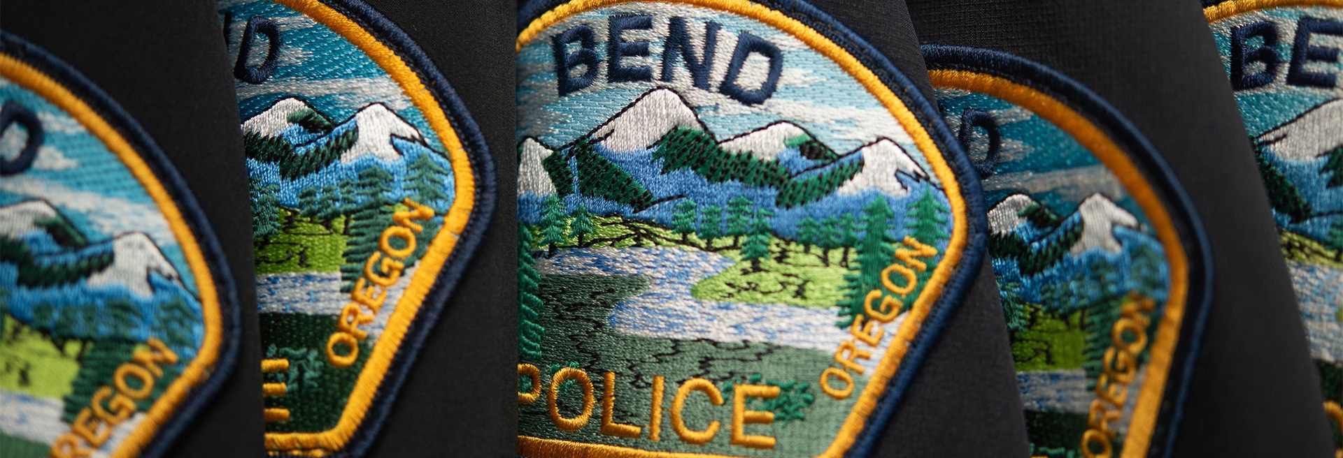 Navy colored shirts hanging up with a Bend Police patch showing on the shoulder.