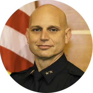 Chief Krantz has fair complexion and is wearing a navy blue police uniform. 