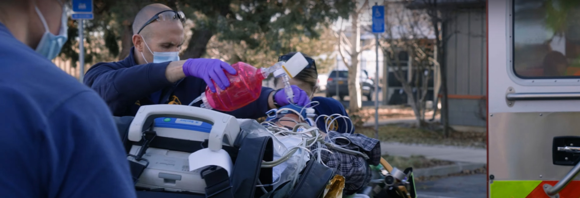 First responders working on a patient on a gurney outside of an ambulance.