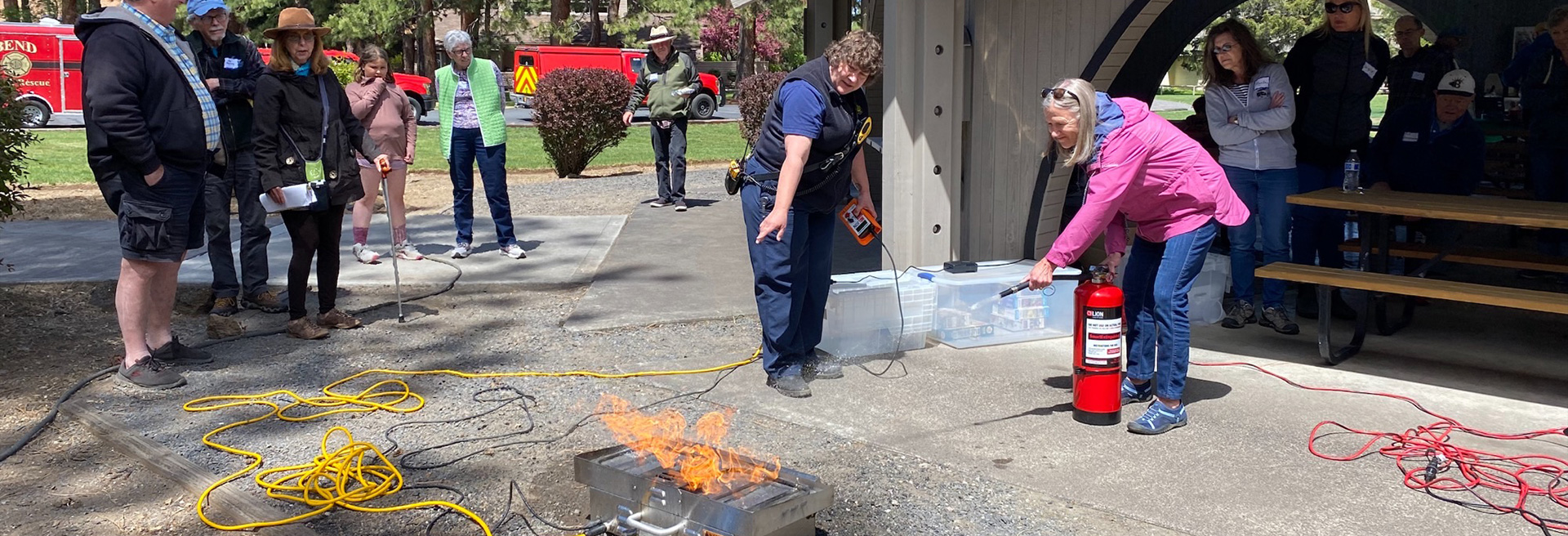 A small fire being put out with a Fire Extinguisher by a community member. Fire & Rescue staff are training and monitoring. 