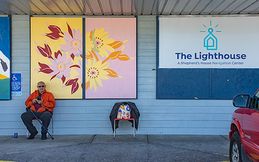 Exterior of the Lighthouse Center, Blue siding, widows with colorful flowers painted on them.