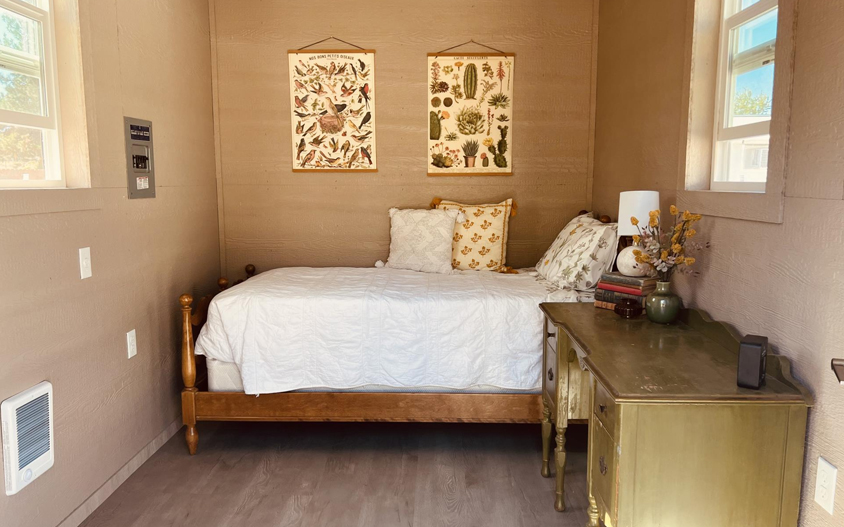 Interior of a room, light brown walls, a bed and desk are inside the room.