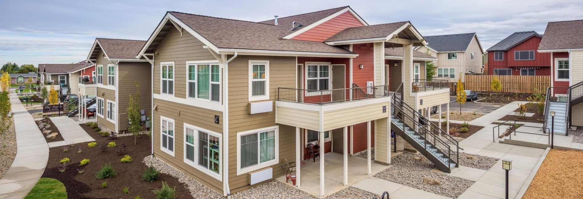 Apartment buildings from the outside. Brown and red colors on the buildings, landscaped with grass and sidewalks.