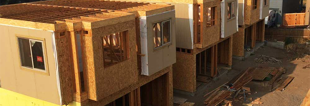 Apartment complex under construction. Buildings are unfinished showing sheathing and no doors or windows.