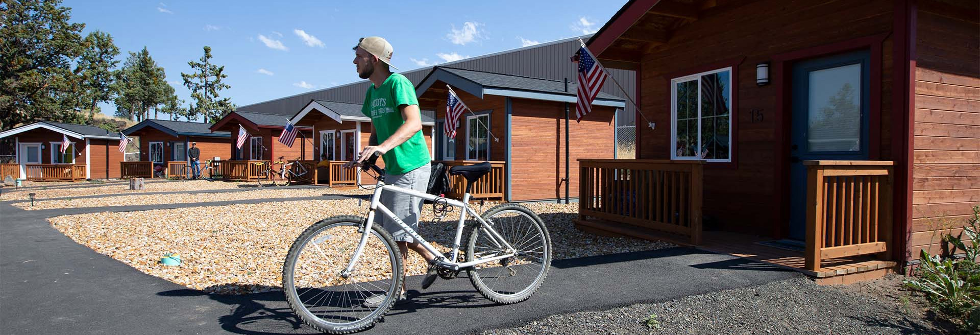 Person walking a bicycle outside of a house, other houses are shown in a complex.