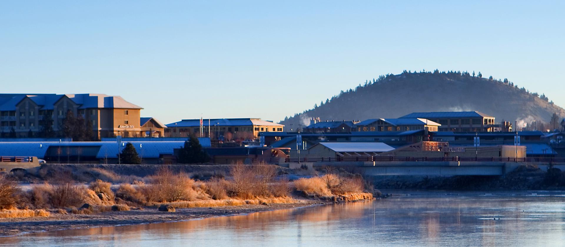 Deschutes River with a snowy downtown Bend in the background and Pilot Butte in the distance.